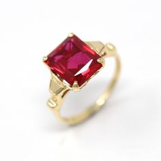 Elegant and classic vintage 10k yellow gold retro 1940s ring featuring a created ruby. The deep red stone is emerald cut, beautifully faceted, weighs approximately 3.60 cts, and is securely prong set. A stunning piece of fine jewelry, featuring July's birthstone color and rose cut accent diamonds! ERA - Circa 1940s, Retro METAL / MATERIAL - 10k yellow gold, created ruby stone (approx. 3.22 ct). (contains essentially the same chemical composition & properties as its natural counterpart, but creat Classic Red Ruby Ring With Prong Setting, Classic Red Solitaire Ruby Ring, Classic Red Birthstone Ring With Prong Setting, Red Classic Birthstone Ring With Prong Setting, Classic Solitaire Ruby Ring With Lab-created Ruby, Classic Red Rings Stamped 14k, Classic Red Sapphire Promise Ring, Classic Ruby Birthstone Ring, Classic Red Birthstone Ring For Anniversary