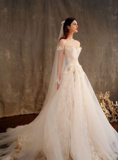 a woman in a wedding dress standing on a wooden floor with her veil pulled back