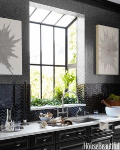 a kitchen with black cabinets and white counter tops is featured in the article, herbs are planted in the base of the solar - style window