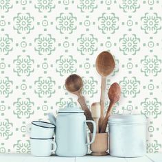 there are many spoons and pots on the counter next to each other, with a wallpaper in the background