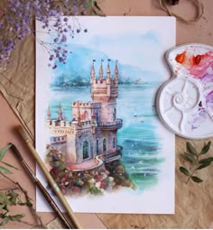 a watercolor painting of a castle next to some paintbrushes