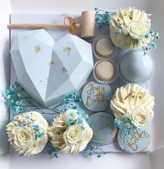 a box filled with cupcakes and flowers on top of a white tablecloth