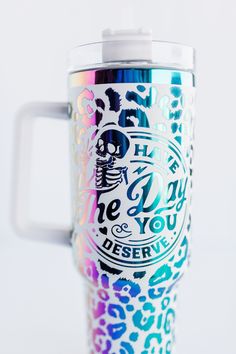 a colorful coffee cup sitting on top of a white table next to a blue and pink leopard print mug