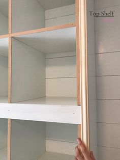 someone is holding the bottom half of a shelf in order to fit it's shelves