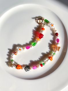 This colorful cottagecore beaded pearl choker necklace is a cute playful mix of nature-inspired elements                    * mix of real freshwater pearls in various shapes and sizes * lampwork glass beads: orange strawberry, brown and orange mushrooms, red raspberry and daisy flower  * mother of pearl leaf beads in fuchsia * czech glass beads including brown flower, butterfly and ladybug bead * green millefiori flower shape beads The necklace is finished with a 18k gold-plated toggle clasp Siz Daisy Pearl Necklace, Pearl Necklace Colorful, Colorful Cottagecore, Flower Beaded Necklace, Cottagecore Jewelry, Leaf Beads, Brown Flower, Necklace Colorful, Red Raspberry