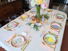 the table is set with plates, cups and vases