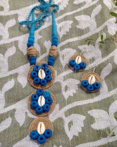 the necklace and earrings are made out of blue beads with white shells on them, sitting on a patterned cloth