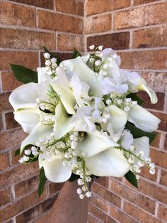 a bouquet of white flowers sitting in front of a brick wall