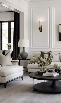 a living room filled with white furniture and lots of black and white decor on the walls