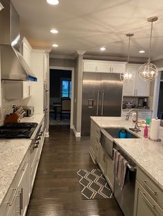 a kitchen with stainless steel appliances and marble counter tops, along with hardwood flooring