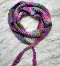 a multicolored knitted scarf with tassels on top of white fur