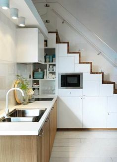 a kitchen with a sink, microwave and stairs leading up to the upper floor area