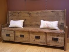 a wooden bench with three drawers and two white pillows