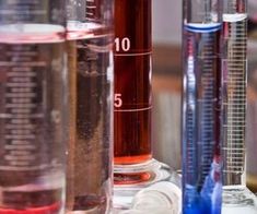 three different types of laboratory equipment sitting on a table with blue and red liquids in them