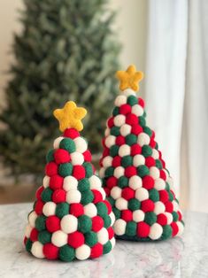 two knitted christmas trees sitting on top of a table