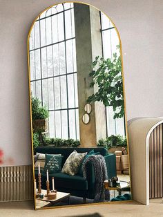 a living room with a green couch and large mirror in it's center area