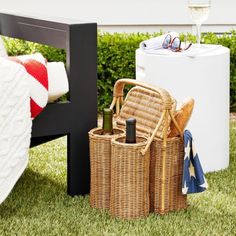 a picnic table with wine bottles and glasses on it next to a basket filled with drinks