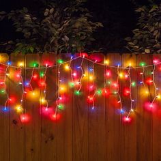 christmas lights are hanging on a wooden fence