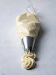 a white frosted cupcake being piped with icing