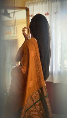 a woman standing in front of a mirror with her hand on her head and looking into the mirror