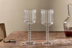 two wine goblets sitting on top of a wooden table next to a bottle