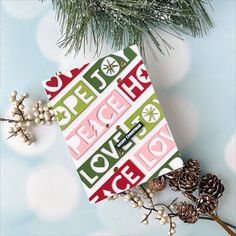 a christmas card sitting on top of a table next to pine cones