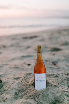 a bottle of wine sitting in the sand