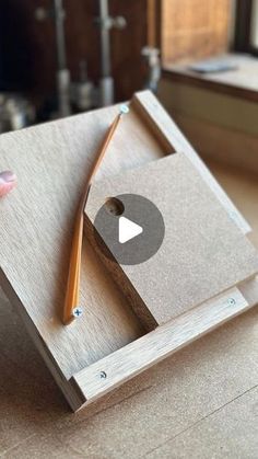 a person is holding a wooden box with a pencil in it and an arrow on the side