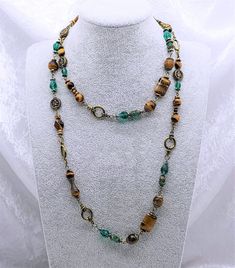 Necklace with matching set of earrings combining an elegant design approach with ethnic motifs, femininity and emancipation. The set is made with bronze findings and natural Tiger's Eye stone(10 & 8mm) beads and Green Crystal Glass beads. Necklace length: 98cm/38.5in Beautiful and attractive necklace make you charmer and elegant. Wonderful gift for you and your female friends. All of my jewellery is handmade, by me.  Every item is made personally with each one taking several hours of painstaking work.  Each item is made carefully with great attention to detail to ensure the highest possible quality. Please have a look at the other items I have for sale in my Etsy Shop or my own website larajolycraft.com Feel free to contact me at any time if you have questions. Should you buy my jewellery, Multicolor Round Copper Jewelry, Artisan Jewelry With Spacer Beads For Gifts, Bohemian Long Round Necklace For Gift, Artisan Spacer Beads Jewelry As Gift, Bohemian Long Round Necklace As Gift, Bohemian Round Long Necklace Gift, Bohemian Long Round Necklace Gift, Bohemian Style Long Round Necklace Gift, Bohemian Gold Jewelry With Artistic Design