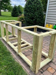 a wooden planter box sitting on top of a brick walkway next to a house