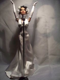 a barbie doll wearing a white dress and holding a microphone