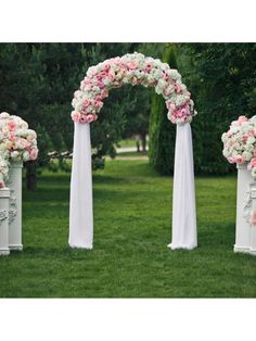 an outdoor ceremony setup with white and pink flowers on the arch, along with other floral arrangements