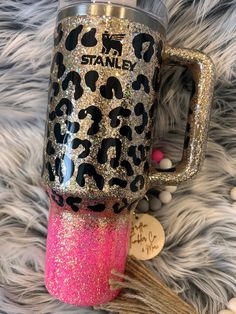 a pink and black leopard print coffee cup with the words stand on it, sitting on a furry surface