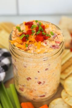 a glass jar filled with food sitting on top of a table next to crackers