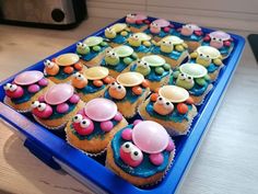 cupcakes with colorful frosting and decorations on them in a blue plastic container