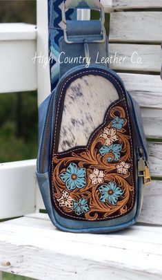 Here's the super popular sling bag with an added tooled leather patch. This patch features a hand tooled floral design with a speckled black and white cowhide inlay. The sling bag is a gorgeous blue gray color with an adjustable strap. Sling bag has two pockets, the front pocket is smaller and has some card slots, the rear pocket is larger and can fit all the necessities: phone, wallet, keys, check book, etc. Sling bag measures 5"x 9" x 3" PLEASE READ: This item is for pre-ordering, and is made to order! Once purchased, this item will take approximately two weeks to re-create. Item will be a close replica, but each one will have slight variances in color, carving, etc. as I am not perfect, and leather is not perfect either! Cowhide will also be different. The cowhide will still be black an Hand-tooled Blue Crossbody Shoulder Bag, Hand Tooled Blue Crossbody Bag, Blue Artisan Leather Shoulder Bag, Artisan Blue Leather Shoulder Bag, Blue Leather Artisan Shoulder Bag, Blue Hand Tooled Leather Shoulder Bag, Blue Leather Hand Tooled Shoulder Bag, Hand Tooled Blue Leather Shoulder Bag, Artisan Blue Leather Bag