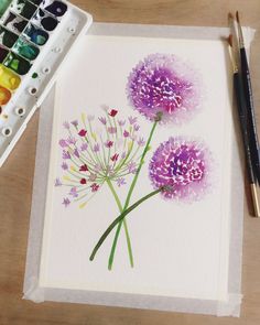 a watercolor painting of purple flowers next to some paintbrushes and a palette