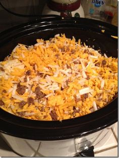 a crock pot filled with cheese and other toppings on top of a stove