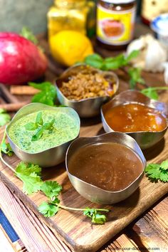 several different sauces and condiments on a cutting board with apples in the background