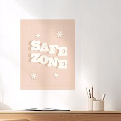 a desk with a book, pen and pencils on it in front of a poster that says safe zone