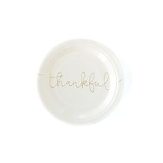 a white paper plate with the word thank written on it in gold foil lettering, against a white background