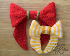 two knitted bow ties on top of a wooden table next to a pair of red and yellow striped hair clips