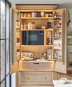 an open cupboard with a microwave and other items in it