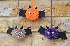 three pom poms hanging from hooks on a brick wall with bats attached to them