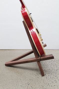 a red and white surfboard sitting on top of a wooden stand