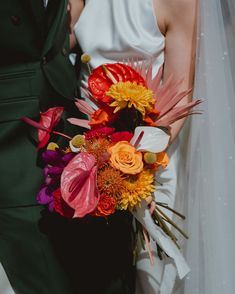 the bride and groom are holding colorful bouquets