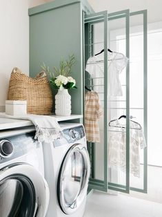 a washer and dryer in a small room with green walls, white tile flooring and open closet doors