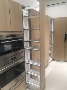 an empty kitchen with stainless steel appliances and wooden cupboards on either side of the oven