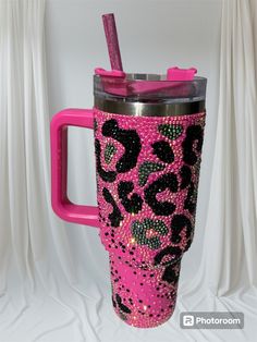 a pink and black leopard print tumbler cup with a straw in the middle, on a white background