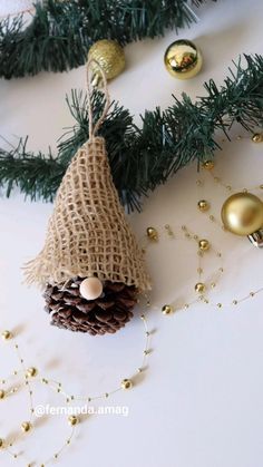 a pine cone ornament hanging from a christmas tree with gold ornaments around it